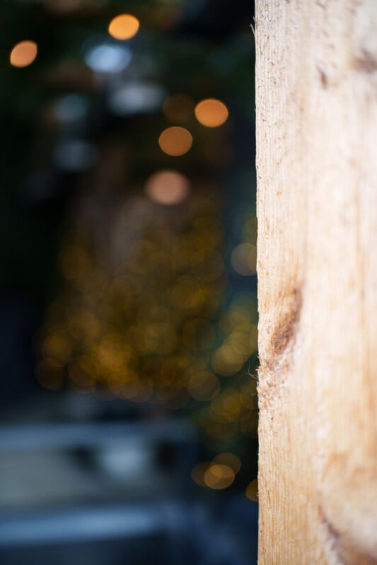 Close-up of a wooden surface on the right, with a blurry background featuring warm yellow bokeh lights creating an abstract pattern.