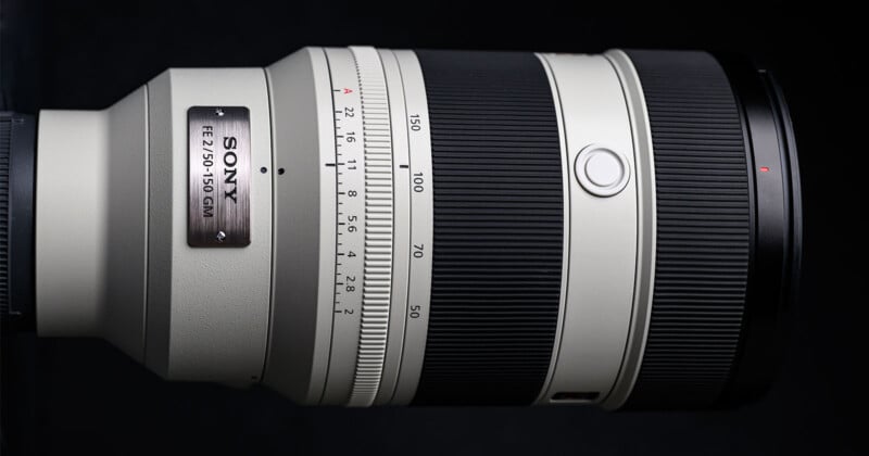 Close-up of a Sony FE 2.8/70-200 GM interchangeable camera lens with a white barrel, black focus and zoom rings, and a metal nameplate, set against a black background.