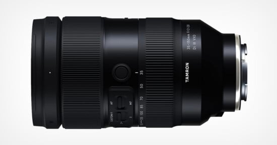 A black camera lens with a sleek design, displaying the Tamron logo and specifications: "35-150mm F/2-2.8 Di III VXD." The lens features manual controls and zoom markings on its surface, set against a light gray background.